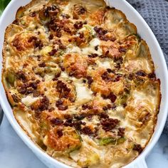 a white casserole dish filled with meat and vegetables on top of a table