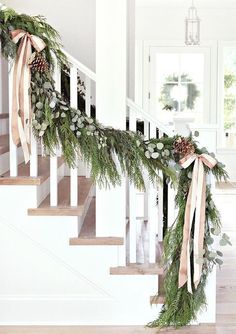 the stairs are decorated with greenery and pine cones for garlands on each handrail