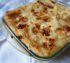 a casserole dish with cheese and bacon in it sitting on a white cloth