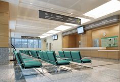 an airport waiting area with blue chairs and a check in counter on the far side