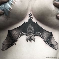 a woman's chest with a bat tattoo on it