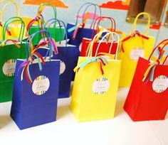 colorful paper bags are lined up on a table with tags attached to the handles and sides