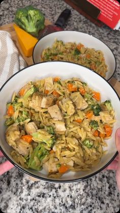 two bowls filled with pasta and vegetables on top of a counter