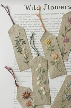 four bookmarks with flowers on them sitting on top of an open page in a book