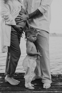 an adult and two children standing on a dock by the water with their arms around each other