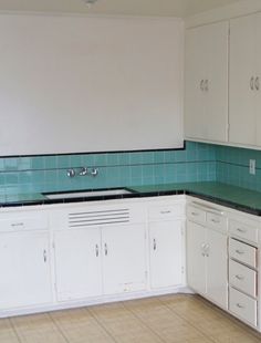 an empty kitchen with white cabinets and green counter tops