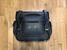 a black leather bag sitting on top of a wooden floor