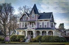 a pink victorian house with white trim on the front porch and two storyed windows