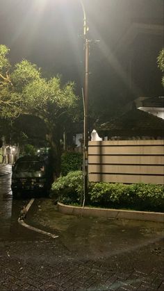 a car is parked in front of a house on a rainy night with the sun shining