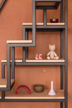 a teddy bear sitting on top of a wooden shelf