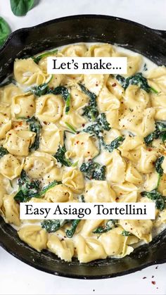 a skillet filled with tortelli and spinach on top of a table