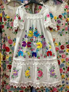 a white dress with flowers on it hanging from a rack