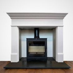 an empty fireplace with a black stove top and wood floor in front of white walls