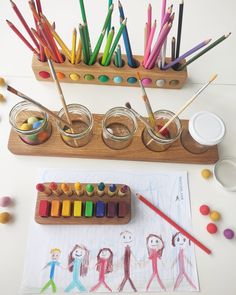 an assortment of colored pencils and crayons in glass containers on a table