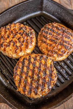 three hamburger patties cooking in a cast iron skillet