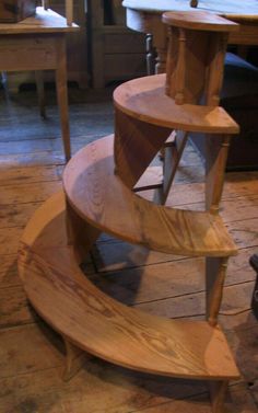 a wooden spiral staircase sitting on top of a hard wood floor next to a table