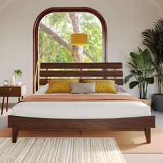 a large bed sitting under a window next to a potted plant and wooden furniture