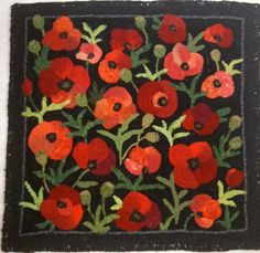 an embroidered square with red and green flowers on black fabric, in the middle of it is