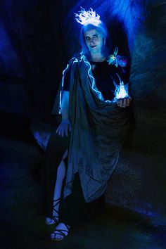 a woman in a dark room with blue lighting on her head and hands holding a lit up object