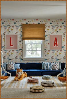 a cat sitting on top of a blue couch in a living room next to a window