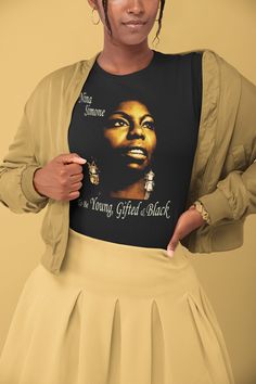 This is a High-Quality, Bella + Canvas 3001 Premium, Soft, Unisex, Short Sleeve Tee Shirt. Stylish Tee in a range of darl colors, featuring legendary Jazz, Blues, Gospel, Funk, Soul and Pop Singer and Piano player Nina Simone with the text 'To Be Young Gifted & Black'. Beautiful Art Print Tee. Ideal casual, fashionable, streetwear for any occasion. Share the Black Lives Matter message in a positive way. This updated unisex essential fits like a well-loved favorite. Super soft cotton and exce Fitted Black Music-themed Top, Fitted Music-themed T-shirt For Streetwear, Fitted Music-themed Streetwear T-shirt, Fitted Music-themed Top With Crew Neck, Black Short Sleeve Music-themed Tops, Black Concert Fan Apparel T-shirt, Black Fan Apparel T-shirt For Concert, Black Music-themed T-shirt With Text Print, Black Music-themed T-shirt With Letter Print