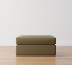 a green ottoman sitting on top of a hard wood floor