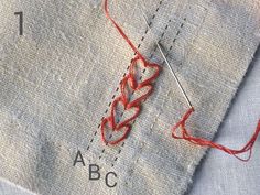 the thread is being sewn together with an orange needle on top of some fabric