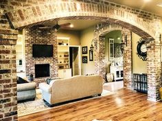 a living room filled with furniture and a fire place next to a brick wall covered in clocks