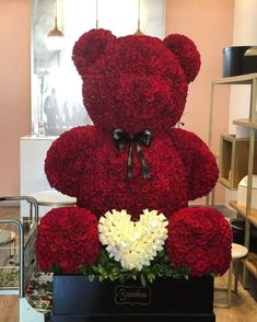 a large teddy bear made out of red roses and white carnations in a black box