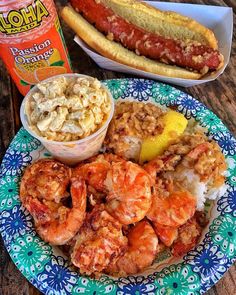 a plate with shrimp, rice and hot dog on it next to a bottle of mustard