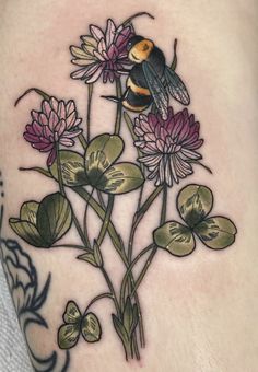 a tattoo with flowers and a bee on it