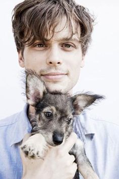 a man holding a puppy up to his face