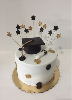 a graduation cake decorated with gold stars and a black cap