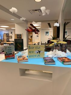 there are many books on the table in this library that is decorated with clouds and an airplane