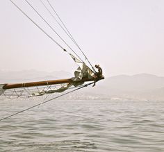 a man sitting on top of a sail boat in the ocean