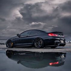 a black sports car parked on the side of a road with dark clouds in the background