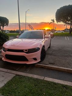 a pink car parked in a parking lot at sunset