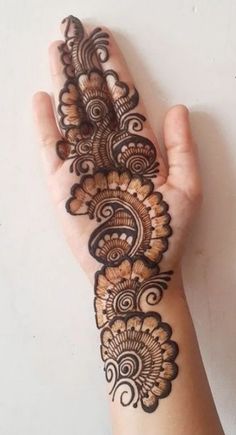 a woman's hand with henna tattoos on her arm and the bottom half of it