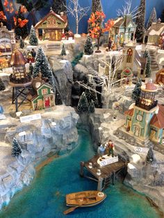 a model village with boats and houses on the water, surrounded by snow covered trees