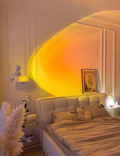 a bed room with a neatly made bed and a large yellow light on the wall