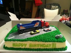 a birthday cake in the shape of a truck and cars