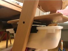 a cat sitting on top of a wooden chair next to a table with a cup