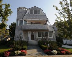 a house that is in the middle of some flowers and bushes on the front lawn