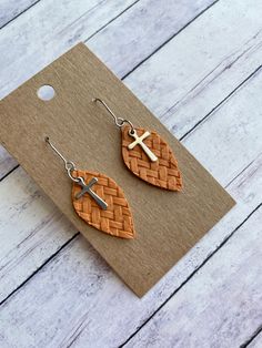 the earrings are made out of woven material and have a cross on top of them