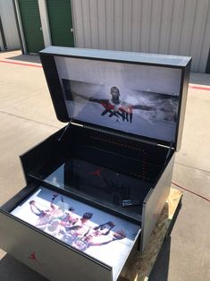 an open box sitting on top of a piece of wood next to a parking lot