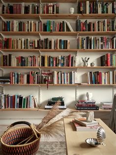 a living room filled with lots of books on top of a wooden shelf next to a window