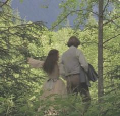 two people are walking through the woods together