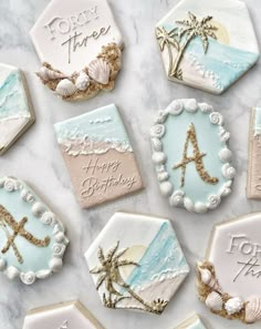 decorated cookies with beach themed icing on a marble table top, including the letter a