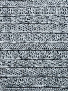 a close up view of the texture of a knitted fabric with horizontal lines in grey and white