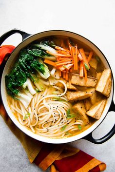 a pot filled with noodles and vegetables on top of a table